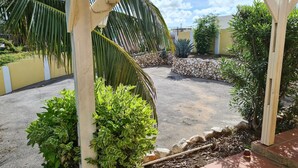 Un pati pavimentat amb una pèrgola, plantes diverses i una paret de pedra.