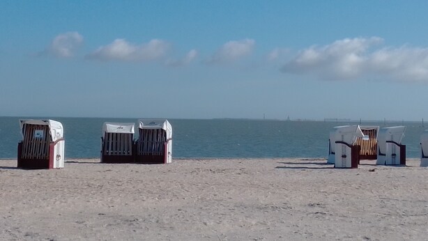 Strandstole ved stranden og en lille bygning i sandet.
