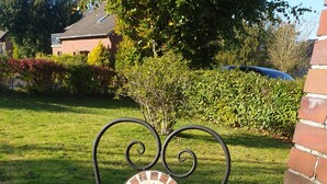 En patio med et rundt bord og en matchende stol, begge med mosaikrygge.