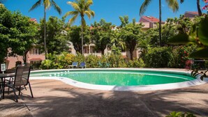 A swimming pool surrounded by palm trees and greenery, with a few lounge chairs and a table nearby. - Emerald Corner @ Fisherman`s Point, Ocho Rios (Ocho Rios)