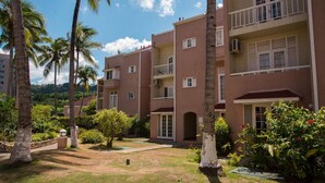 A multi-story building with balconies, surrounded by palm trees and greenery. - Emerald Corner @ Fisherman`s Point, Ocho Rios (Ocho Rios)