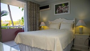 A bedroom with a bed, two bedside lamps, a nightstand, a window with curtains, and a picture on the wall. - Emerald Corner @ Fisherman`s Point, Ocho Rios (Ocho Rios)