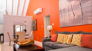 Una sala de estar con un sofá gris, una mesa de centro de madera y un cuadro de árboles en la pared.