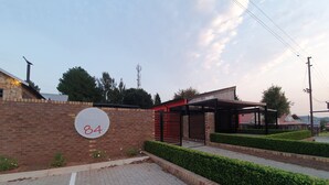 A modern building with a brick facade, a sign indicating room number 84, and a covered outdoor area with a roof. - Sleepat84 (Dullstroom)