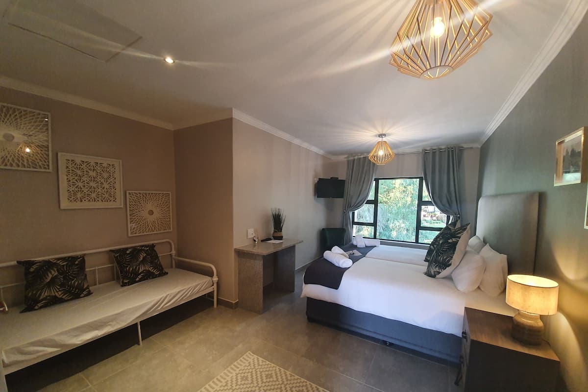 Un dormitorio moderno con cama, sofá, mesita de noche y ventana con cortinas.