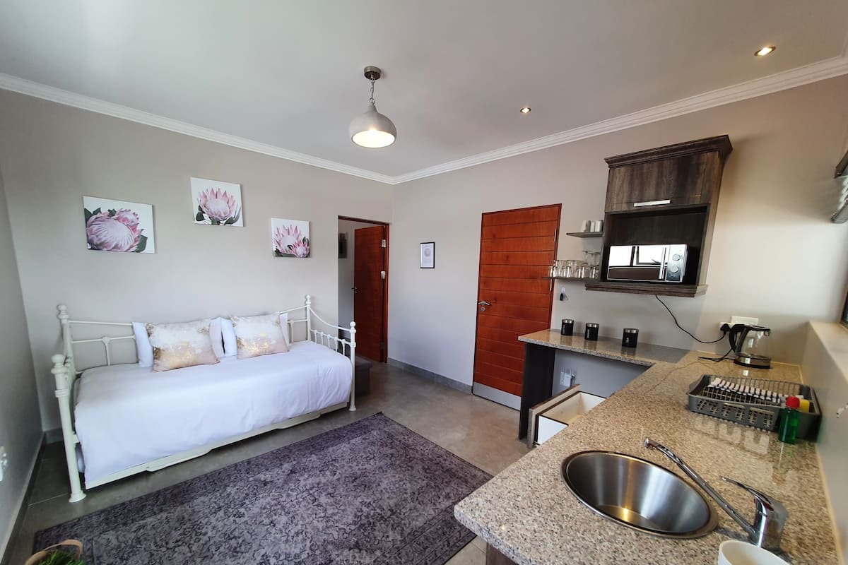 Un dormitorio con cama, un baño con lavamanos y una kitchenette con microondas.