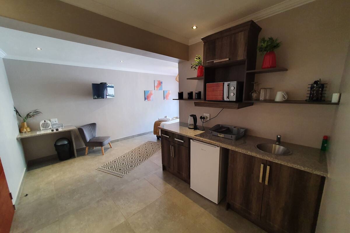 Una cocina moderna con armarios de madera, lavavajillas integrado y una encimera con tetera y cafetera.