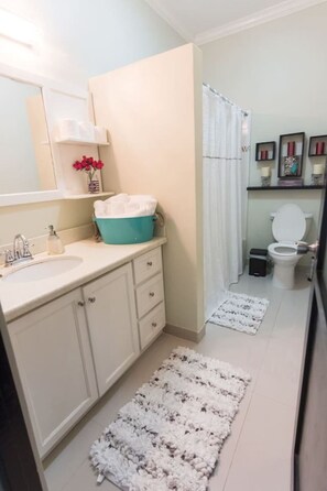 A bathroom with a white sink, a mirror, a blue basin, a white toilet, and a shower curtain. - Seaside Condo 3 (Tower Isle)