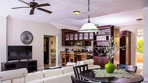 Ein modernes Wohnzimmer mit Sofa, Fernseher und Essbereich mit Tisch und Stühlen.