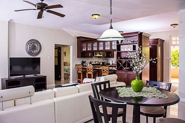 A modern living room with a sofa, TV, and dining area with a table and chairs. - Seaside Condo 3 (Tower Isle)