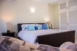 A bedroom with a bed, bedside tables, a lamp, and a wardrobe. - Seaside Condo 3 (Tower Isle)