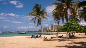 A beach with palm trees, a clear sky, and a hotel in the background. - Sunburst Studio Suite @ Sandcastles Resort (Ocho Rios)