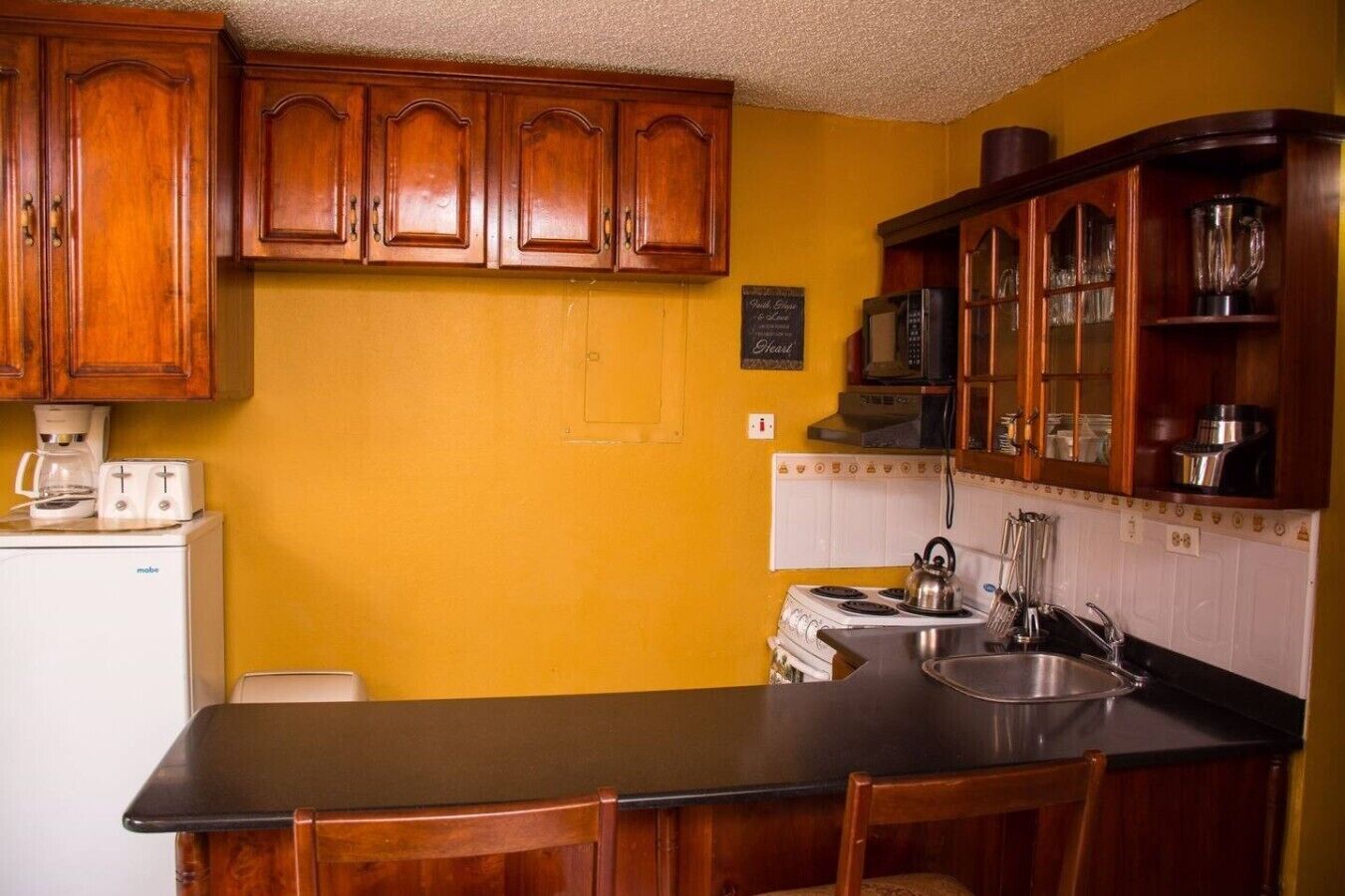 A kitchen with wooden cabinets, a stove, a sink, and a coffee maker.