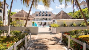 A resort with a swimming pool, palm trees, and a large building with multiple roofs. - Sunflower Serenade (Ocho Rios)