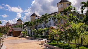 A large building with multiple towers, surrounded by palm trees and a paved walkway. - Sunflower Serenade (Ocho Rios)