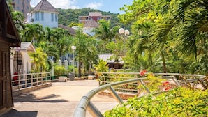 A pathway with a metal railing, surrounded by lush greenery and palm trees. - Sunflower Serenade (Ocho Rios)