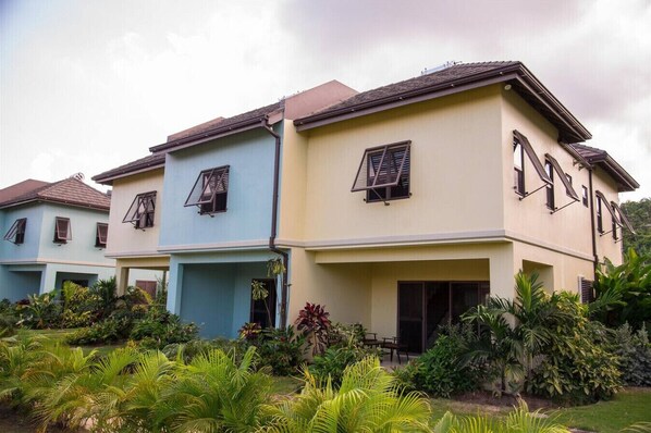 A row of three-story houses with multiple windows and a well-maintained garden in front. - Cabarita Beach Villa (St. Ann)