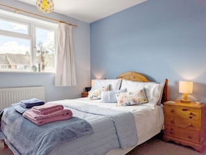 A bedroom with a bed, bedside tables, a window with curtains, and a view of buildings outside.