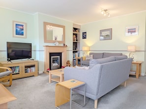 A living room with a television, sofa, fireplace, bookshelves, and a small table.