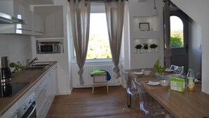 Et moderne køkken med træbordplader, rustfrie stålgre samt et spiseområde med et træbord og stole.