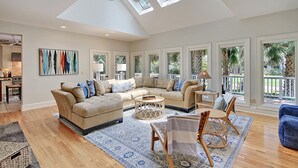 Un salon spacieux avec un haut plafond, de grandes fenêtres et un coin salon confortable.