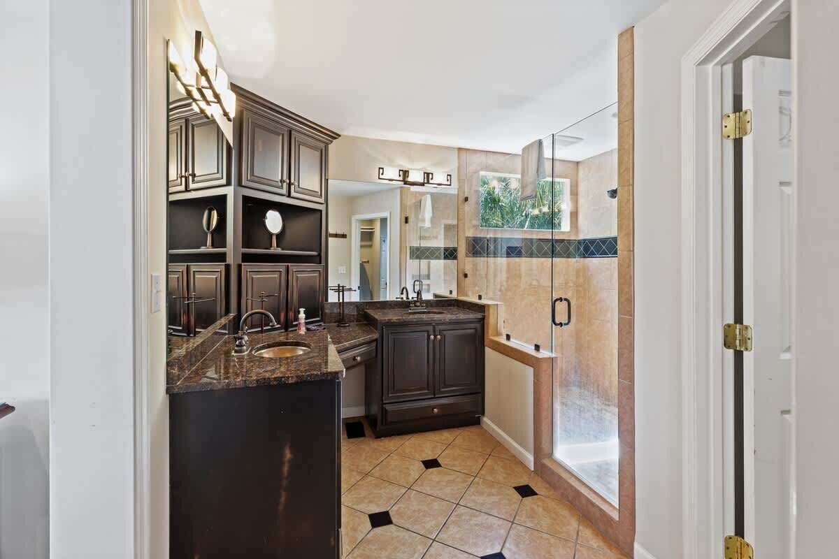 A modern kitchen with dark cabinetry, a granite countertop, and a large window.