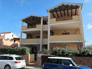 Un edificio de varios pisos con fachada de piedra, balcones y una entrada portonada.