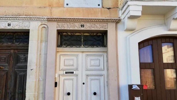 Fachada de edificio con puerta doble, número 22, y buzón.