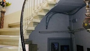 Una escalera con barandales ornamentales y pasamanos, que conduce a un rellano con una puerta y un pequeño marco de cuadro.