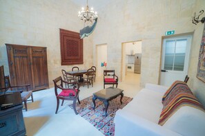 Un salon comprenant un canapé, des fauteuils, une table à manger et un lustre.