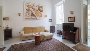 Una sala de estar con un sofá, una mesa de centro, un televisor y un mapa grande en la pared.