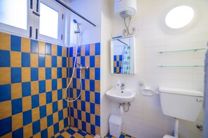 Ein Badezimmer mit Schachbrettfußboden, einer Dusche, einem Waschbecken und einer Toilette.