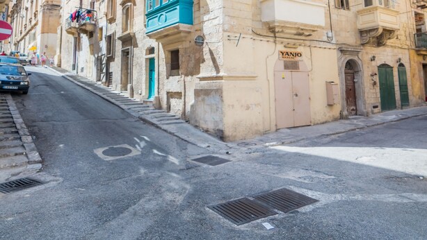 Edifici històric amb façana de pedra, diversos balcons i un comerç a la planta baixa.