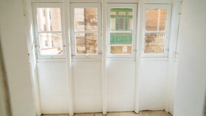 Una habitació amb tres finestres, cadascuna amb una vista diferent de l'exterior. Les parets són de color blanc i el terra està emblat.