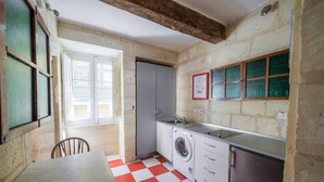 Cuina compacta amb rentadora, un rentaplat i zona menjador amb terra de quadres vermells i blancs.