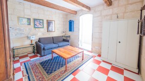 Una habitació amb sòl a quadradets, un sofà, una taula de café, una catifa amb dibuixos i un armari.