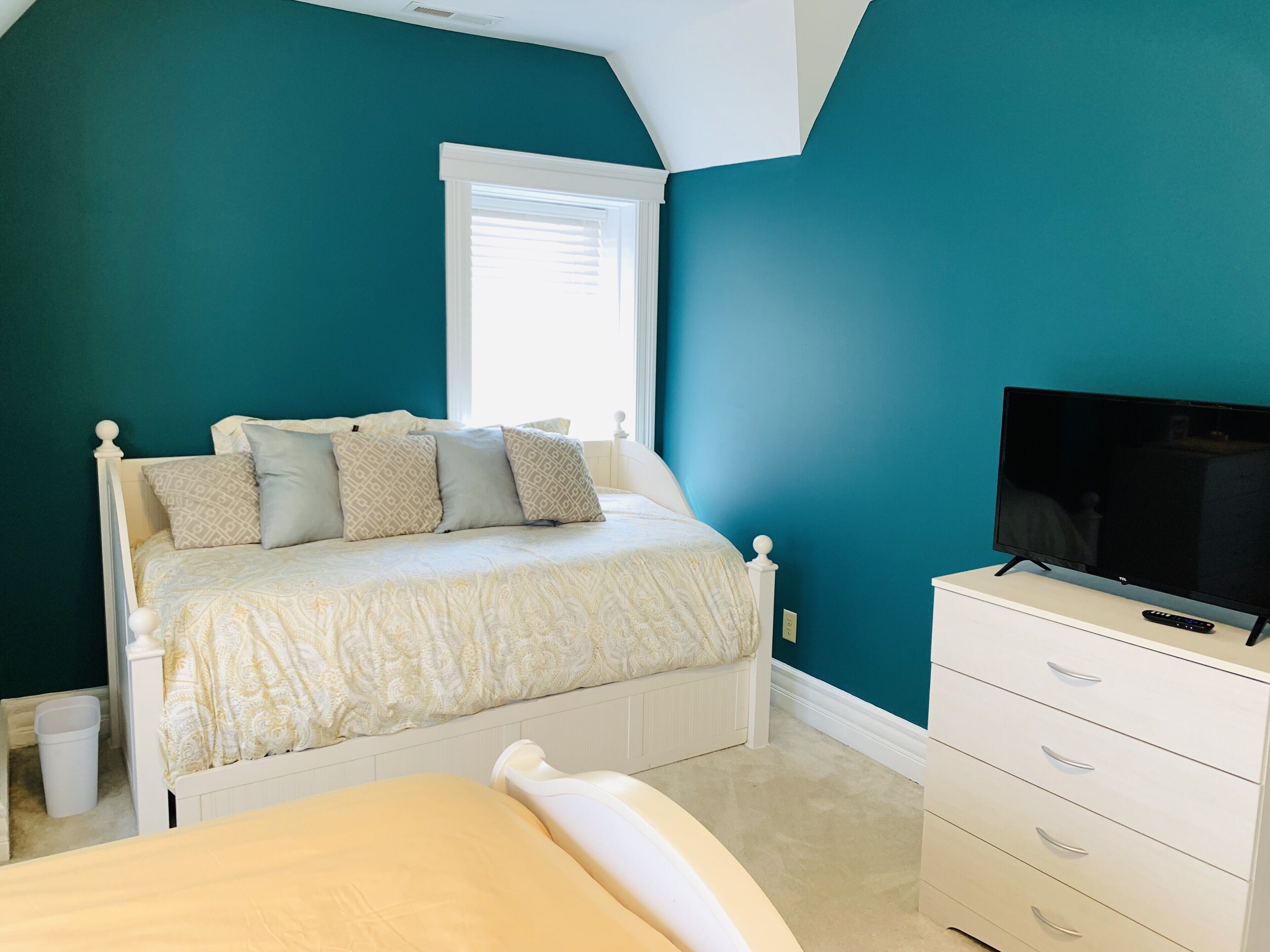 A bedroom with a bed, a TV, and a dresser.