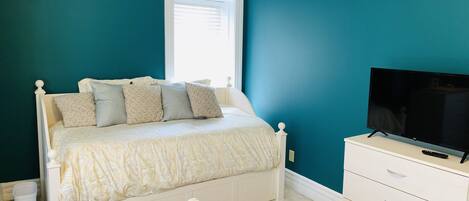 A bedroom with a bed, a TV, and a dresser.