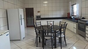 Una cocina con una mesa de comedor y sillas, un refrigerador, un microondas y una estufa.