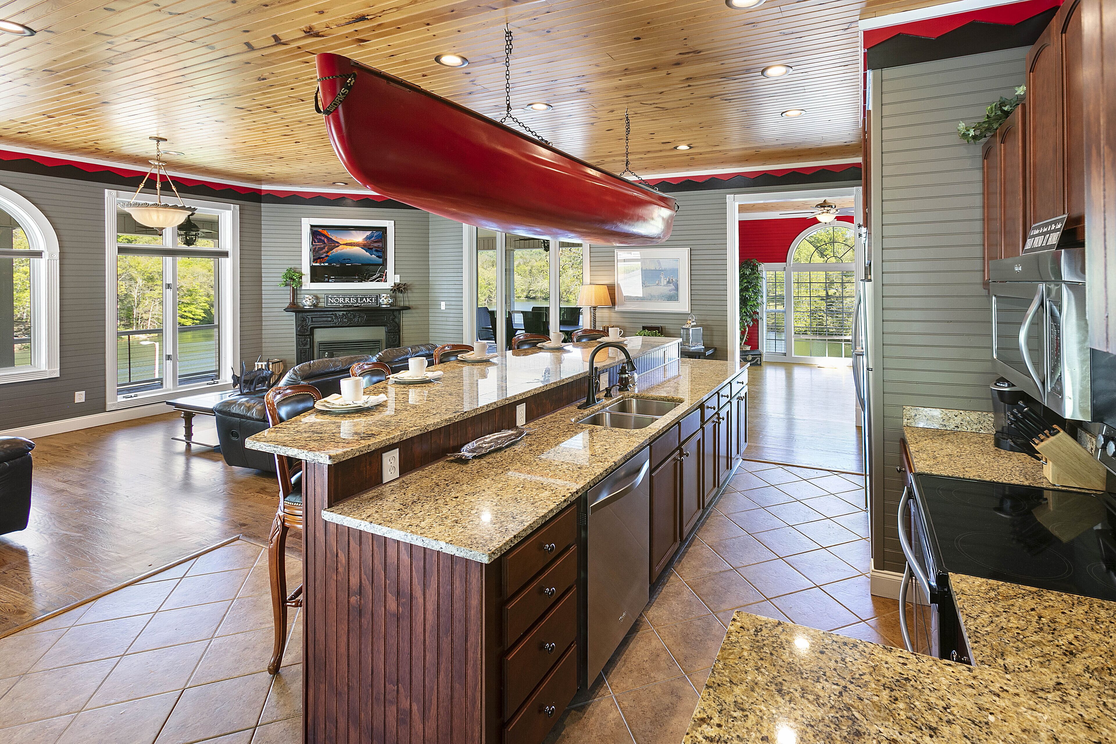 Una cocina amplia con una isla grande, armarios de madera y un colgador para ollas rojo.