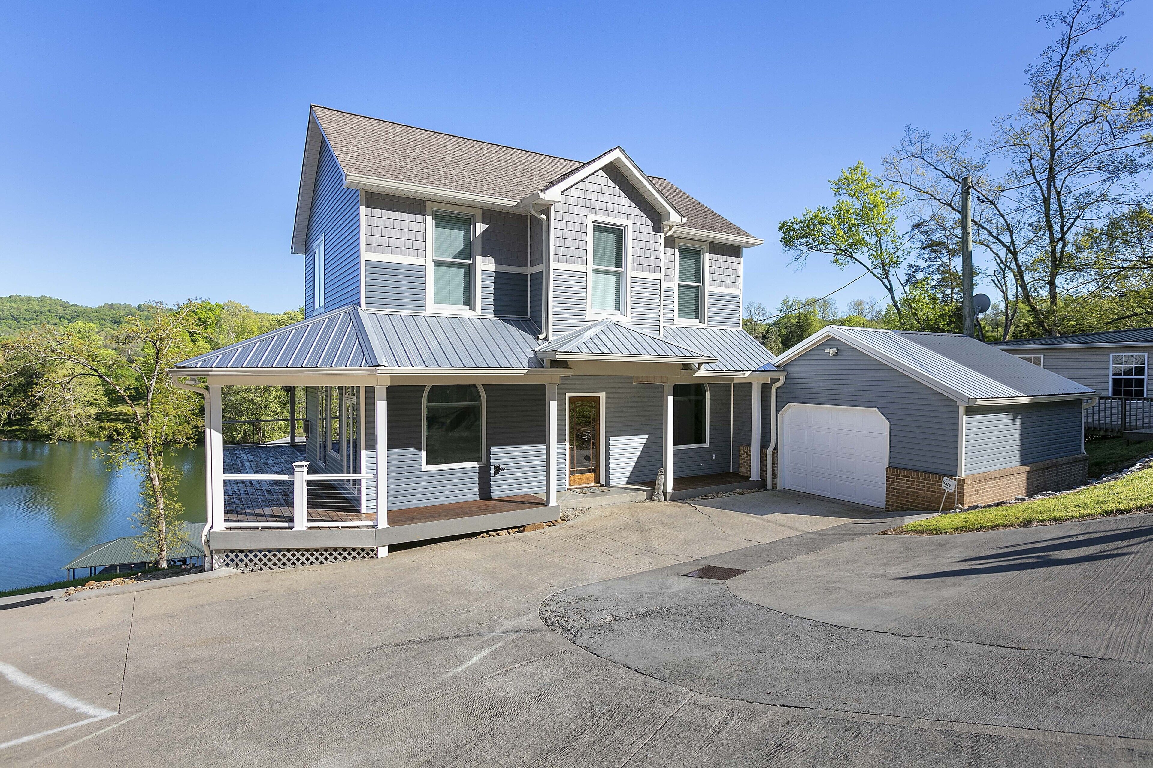 Ein zweistöckiges Haus mit verdeckter Veranda, Garage und Seeblick.