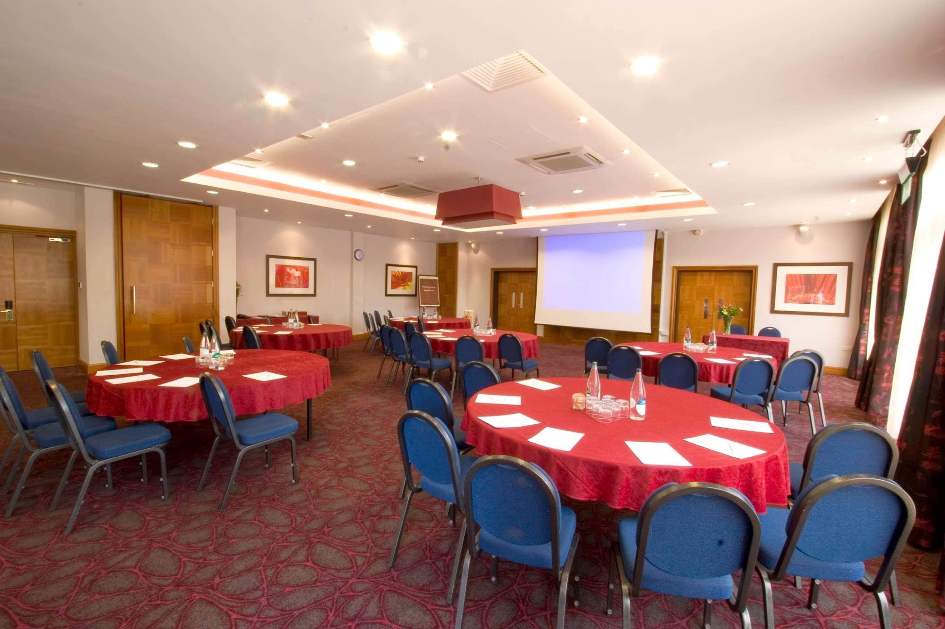 A conference room with multiple tables and chairs, equipped with nameplates and water bottles.