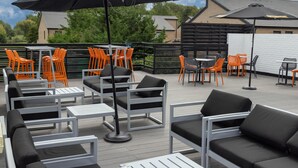 An outdoor patio with seating arrangements, including tables and chairs, and umbrellas providing shade. - Cambridge Bar Hill Hotel, BW Signature Collection (Cambridge)