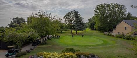 Un parcours de golf doté d’un club-house, d’arbres et offrant une vue sur un ciel dégagé.
