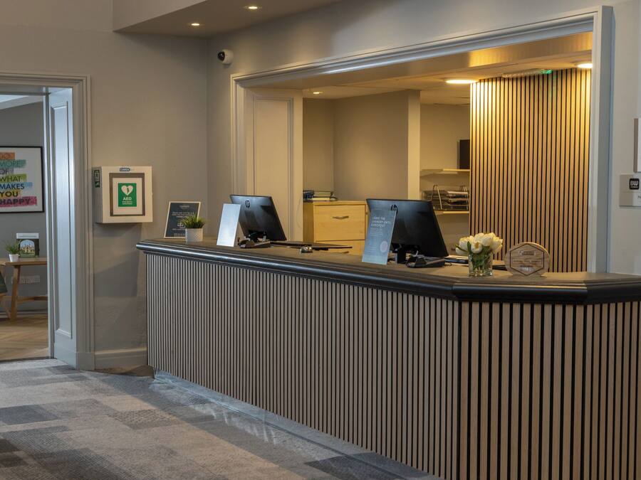 A reception desk with two monitors, a card reader, and a sign for a signature collection.