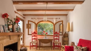 A cozy room with a fireplace, a red sofa, and a dining area with two chairs. - Cosy apartment for 3 people with pool, WIFI, TV and terrace (Denia)