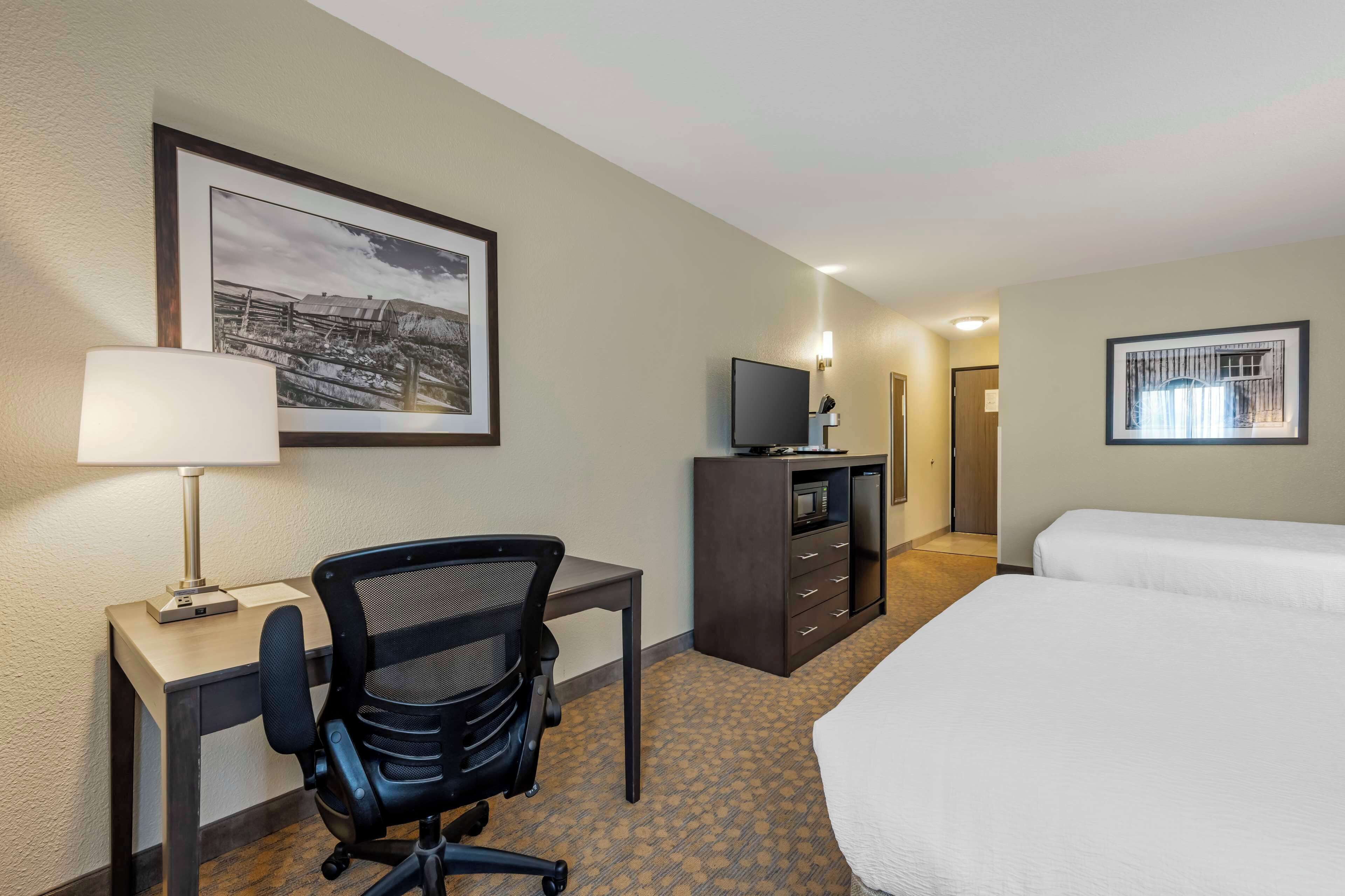 Ein Hotelzimmer mit Bett, Schreibtisch, Stuhl, Fernseher und Bildern an den Wänden.