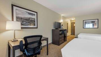 Ein Hotelzimmer mit Bett, Schreibtisch, Stuhl, Fernseher und Bildern an den Wänden.