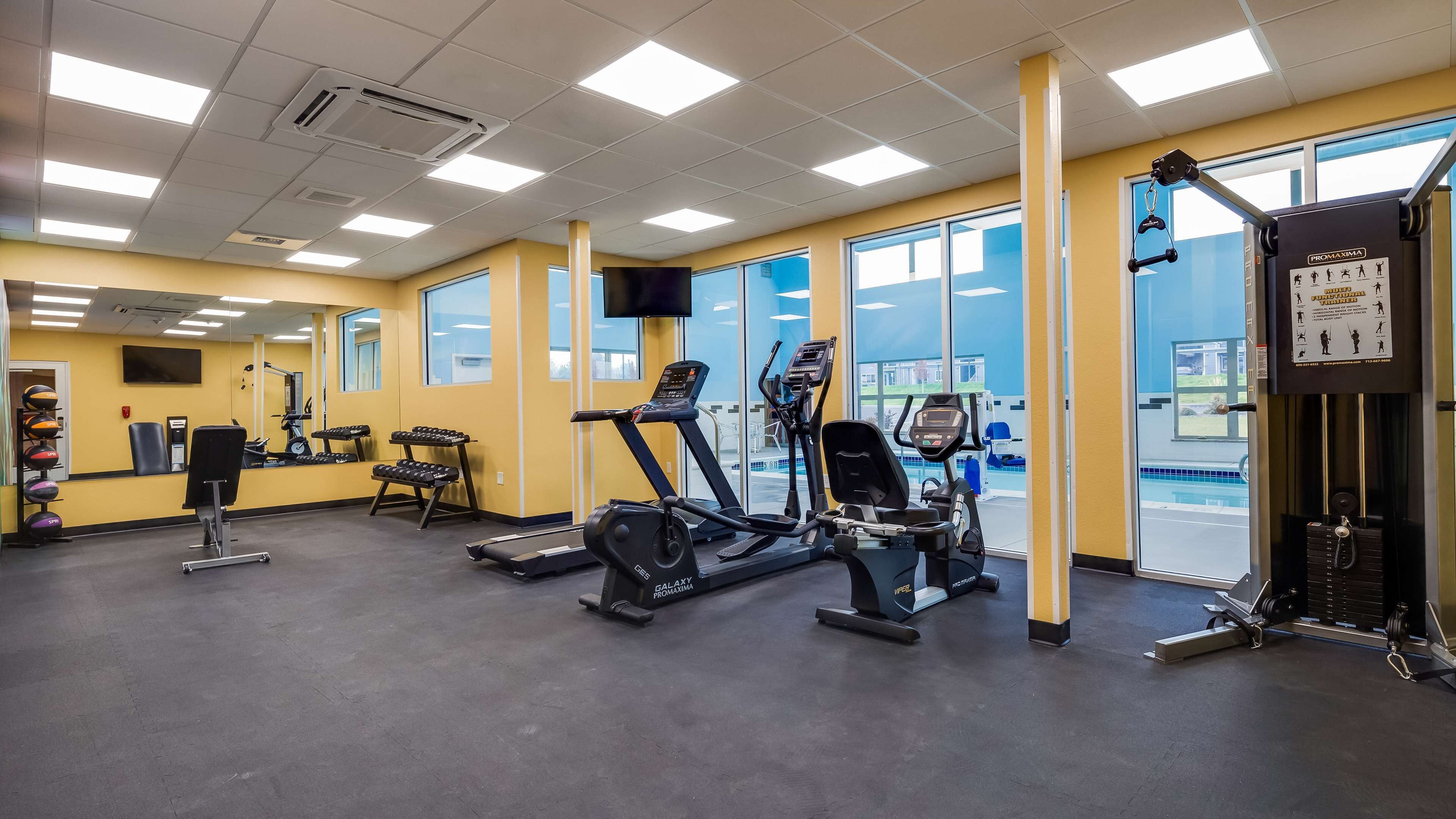 Un gimnasio con cintas de correr, elípticas y equipo de levantamiento de pesas.