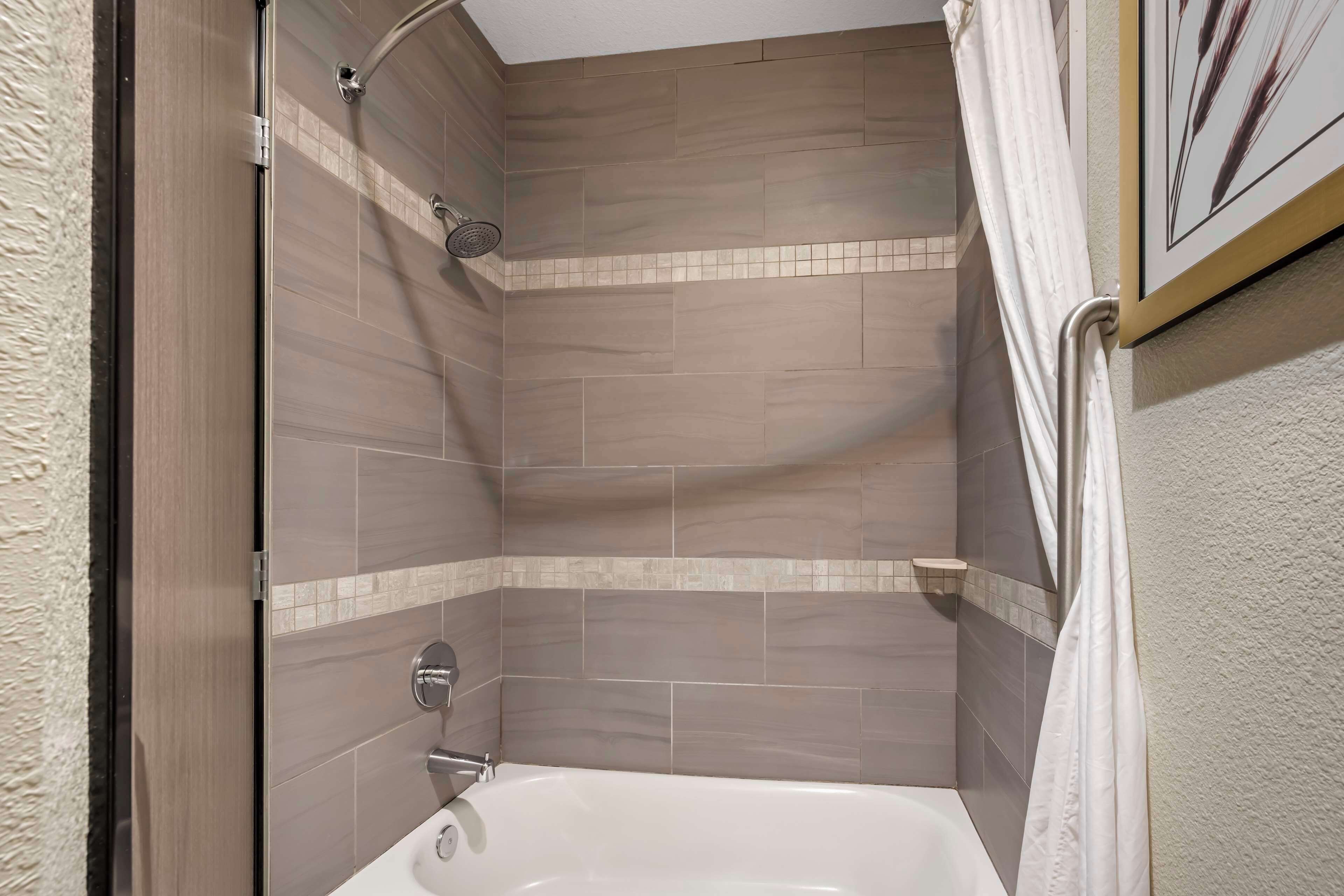 A bathroom with a bathtub, shower, and tiled walls.